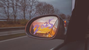 Pictured: Looking into a car's side mirror to view the scenery behind. On the mirror is the year 